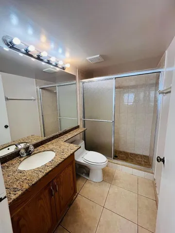a bathroom with a granite countertop sink toilet and shower