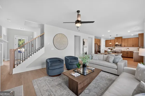 a living room with furniture a rug potted plant kitchen view and a mirror