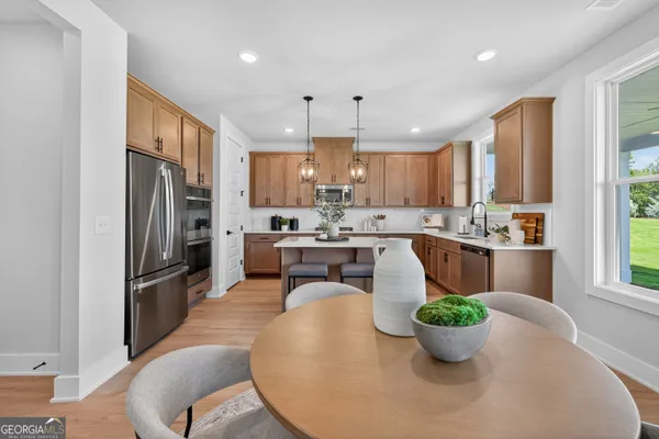 a kitchen with stainless steel appliances granite countertop a refrigerator a sink a stove a dining table and chairs