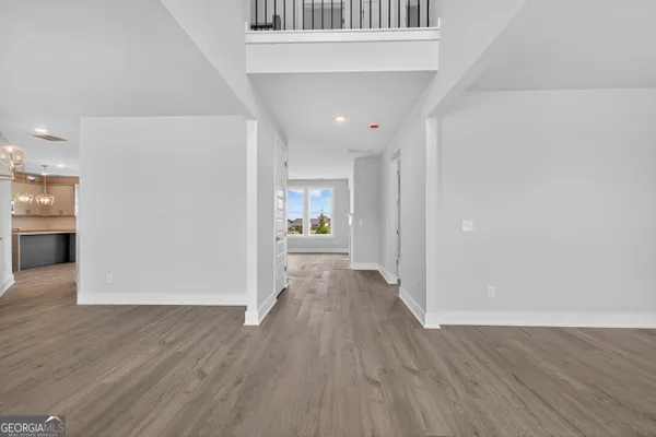 a view of a hallway with wooden floor and a refrigerator