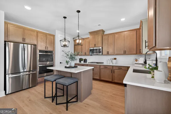 a kitchen with stainless steel appliances granite countertop a sink a stove a refrigerator and island with wooden floor