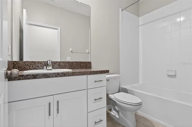 a bathroom with a granite countertop toilet a sink and a bathtub
