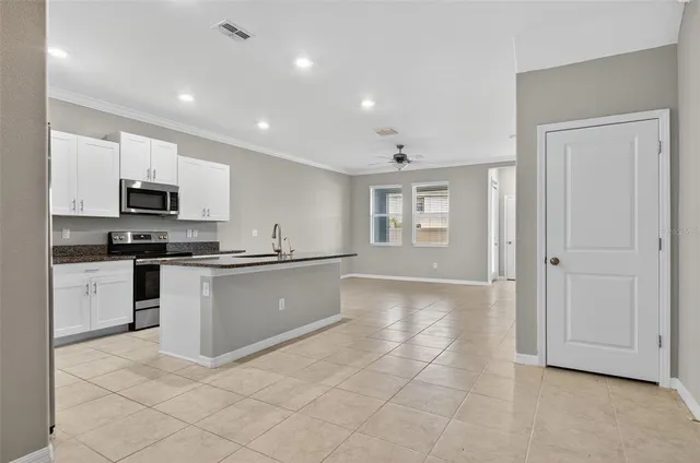 a large white kitchen with granite countertop white cabinets and stainless steel appliances