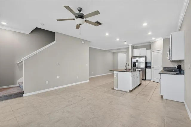 a large white kitchen with kitchen island a sink stainless steel appliances and cabinets