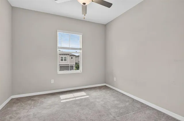 an empty room with a window and chandelier fan
