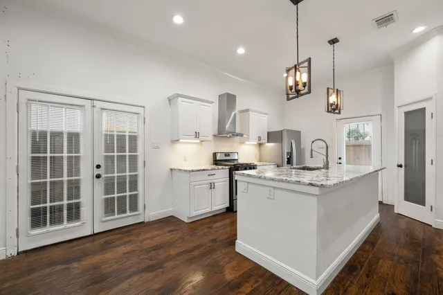 a kitchen with kitchen island granite countertop a sink cabinets and wooden floor