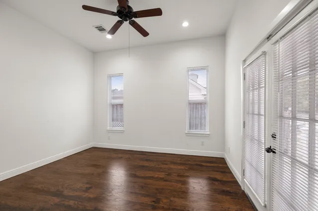 an empty room with wooden floor and windows