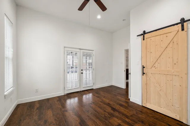 an empty room with wooden floor cabinet and windows