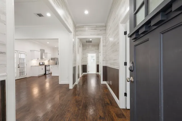 a view of a hallway with wooden floor and a bathroom