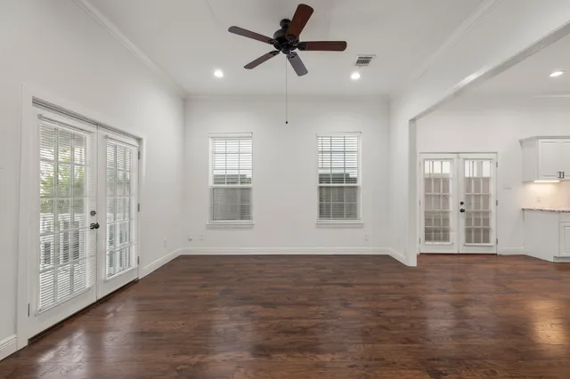a view of an empty room with window and wooden floor
