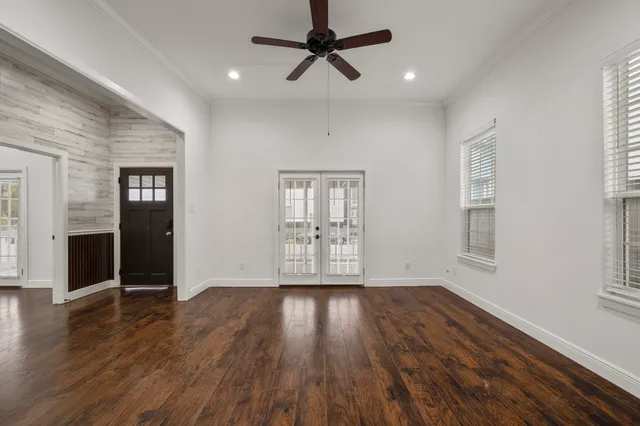 a view of an empty room with wooden floor and a window