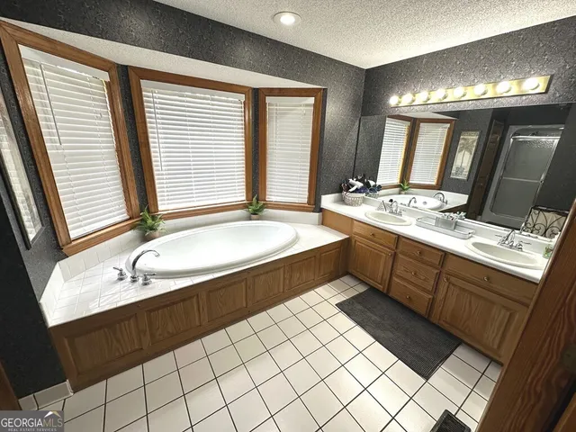 a spacious bathroom with a granite countertop sink and a bathtub