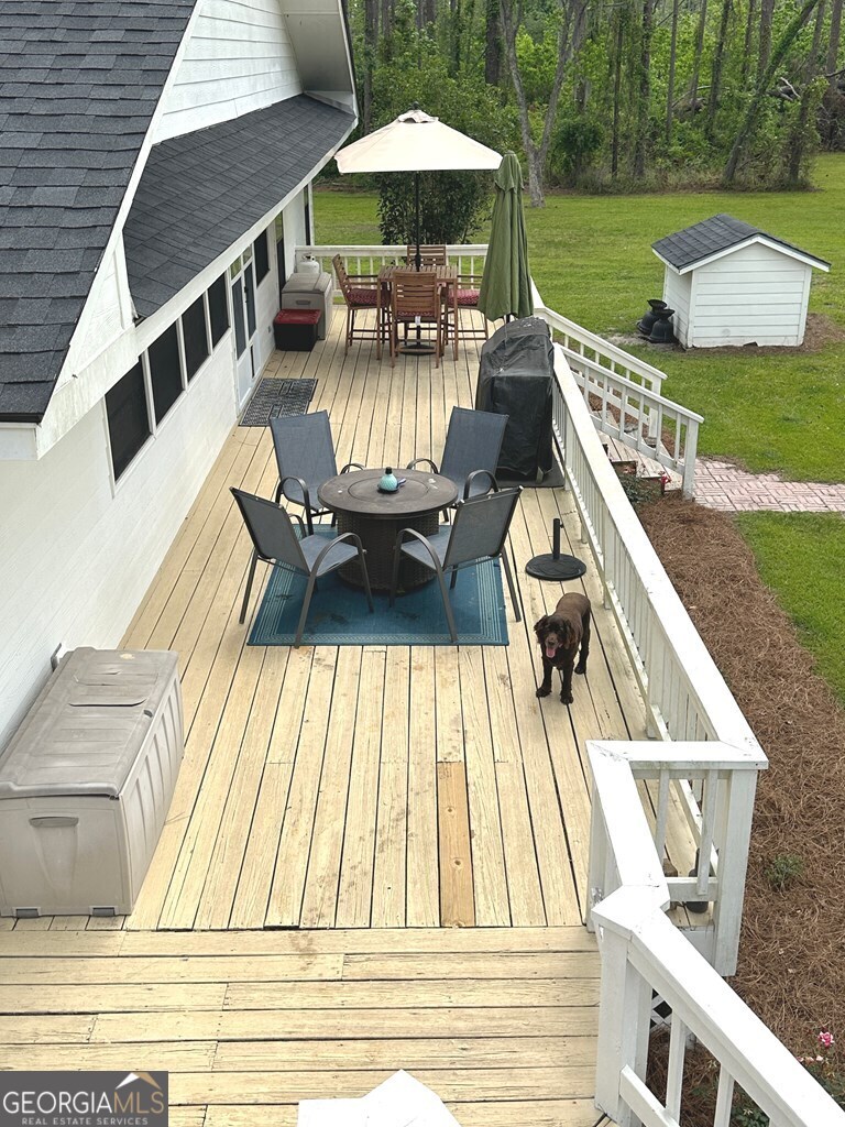 4448 Old Lake Park Road Valdosta, GA 31606 - Photo 26 of 40 a view of a patio with couches table and chairs under an umbrella with large trees