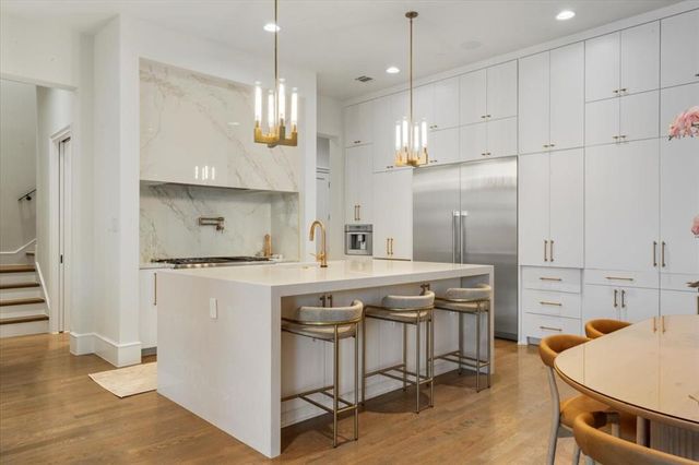 a kitchen with stainless steel appliances granite countertop a sink a stove a refrigerator and island with wooden floor