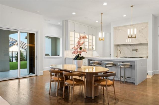 a kitchen with kitchen island a dining table chairs and white cabinets