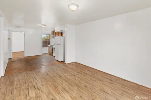 a view of empty room with wooden floor and window