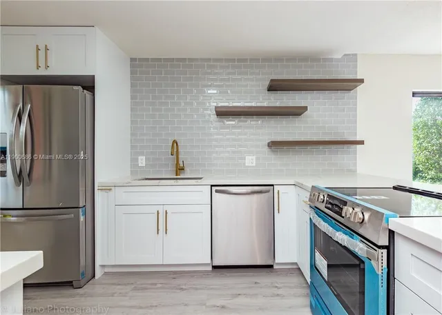 a kitchen with stainless steel appliances a refrigerator a sink and wooden cabinets