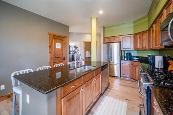 a kitchen with stainless steel appliances granite countertop dining table chairs and wooden cabinets