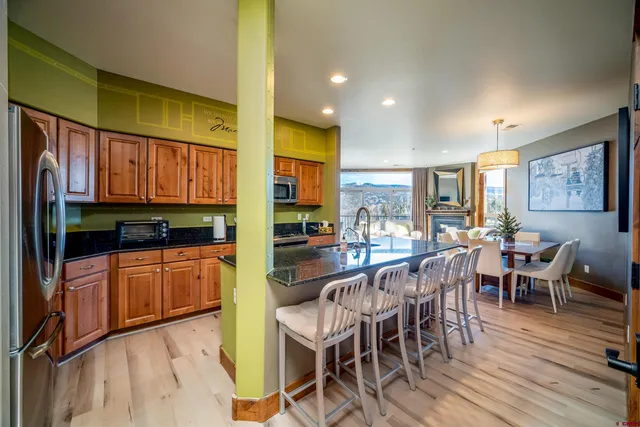 a kitchen with stainless steel appliances granite countertop dining table chairs and wooden cabinets