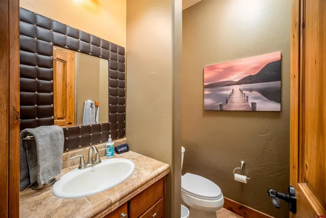 a bathroom with a granite countertop sink a toilet and a mirror