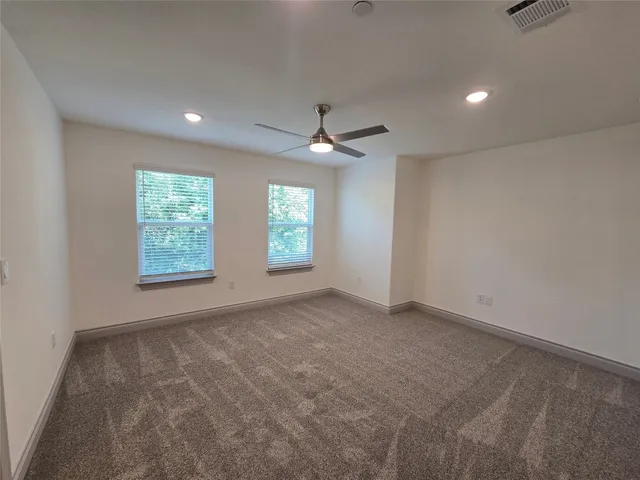 an empty room with windows and ceiling fan