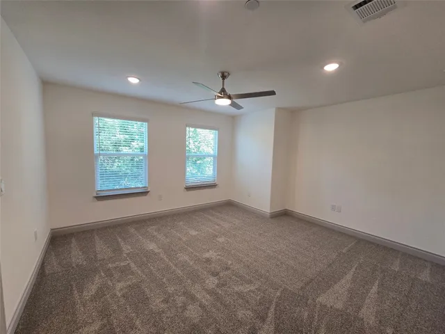 an empty room with windows and ceiling fan