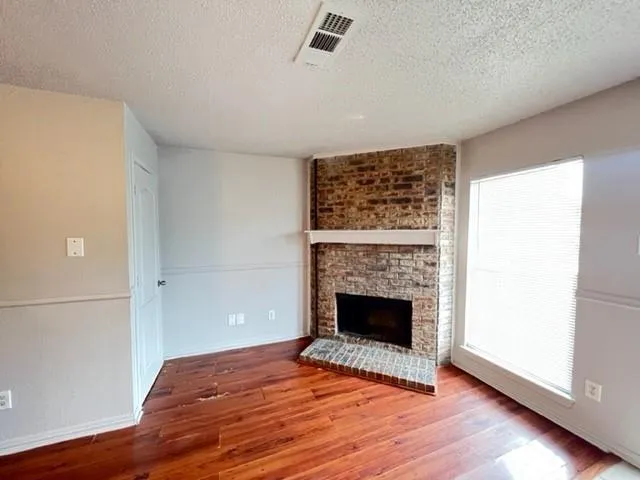 a view of empty room with wooden floor and fireplace