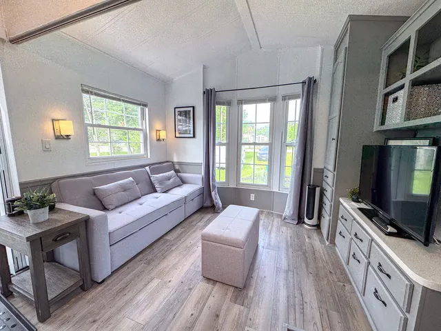 a living room with furniture a flat screen tv and a window
