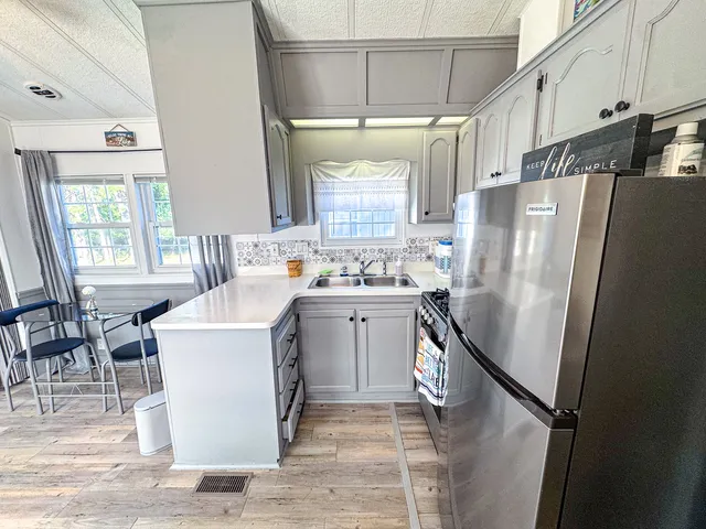 a kitchen with a refrigerator a stove a sink and a dining table with wooden floor