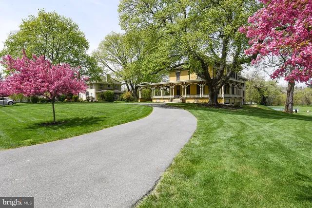 a view of a house with a big yard and large trees