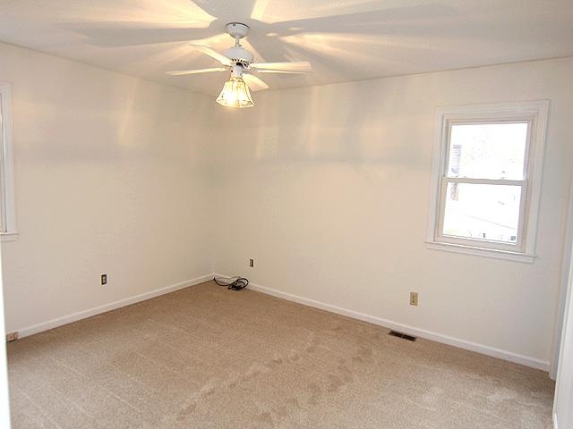 5521 Mapleridge Road Raleigh, NC 27609 - Photo 16 of 24 an empty room with a chandelier fan and windows