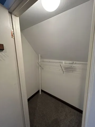 an empty room with a chandelier fan and windows