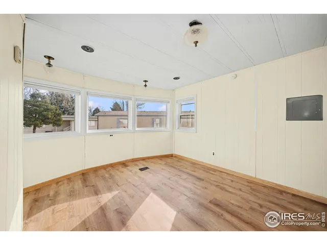 a view of empty room with wooden floor and fan