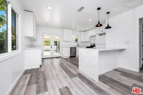 a kitchen with stainless steel appliances kitchen island wooden floors and white cabinets