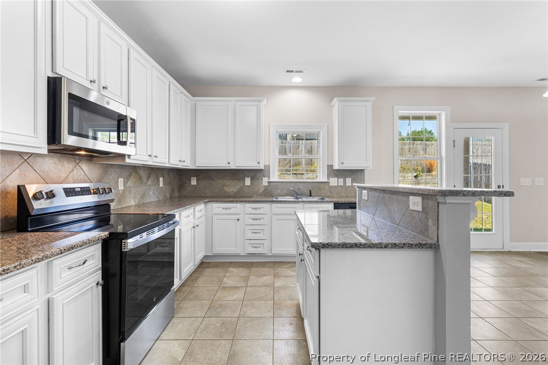 50 Huzzas Circle Cameron, NC 28326 - Photo 12 of 39 a kitchen with stainless steel appliances granite countertop a sink and dishwasher a stove top oven with wooden floor