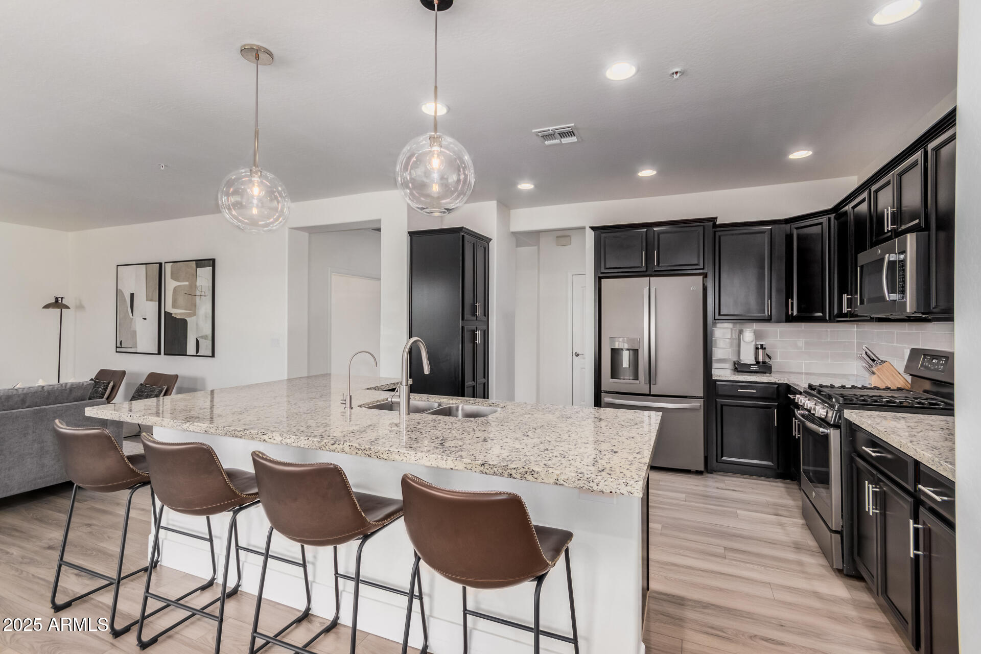 2425 West Bronco Butte Trail, Unit 2010 Phoenix, AZ 85085 - Photo 12 of 44 a kitchen with stainless steel appliances kitchen island granite countertop a dining table chairs refrigerator and cabinets