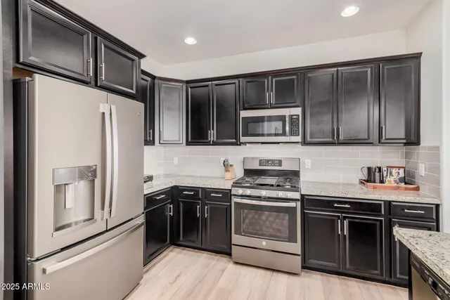 a kitchen with stainless steel appliances granite countertop a stove top oven a sink and refrigerator