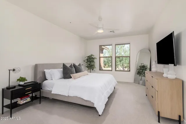 a bedroom with a bed a flat tv screen and a dresser