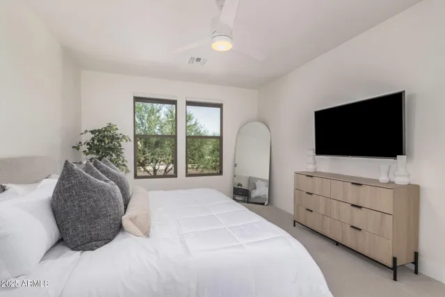 a bedroom with a bed and a flat tv screen on dresser