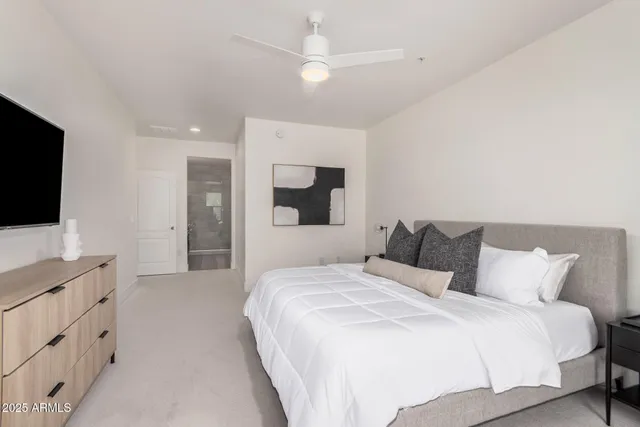 a bedroom with a bed and a flat tv screen on dresser
