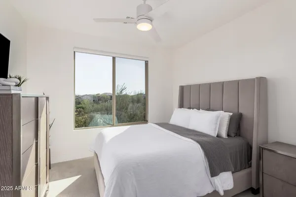 a bedroom with a large bed and a flat tv screen on dresser