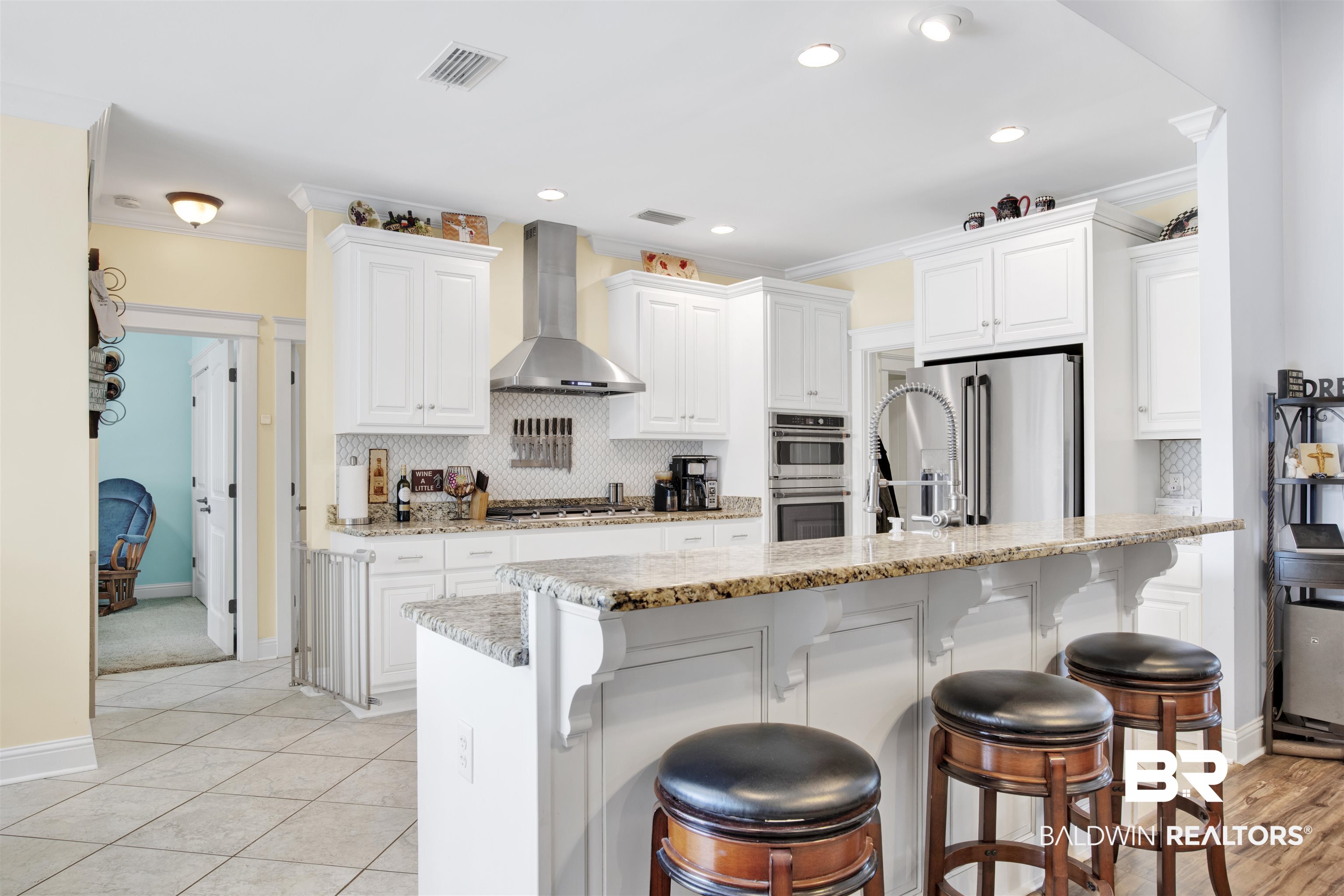 12418 Cambron Trail Daphne, AL 36527 - Photo 20 of 44 Kitchen featuring ornamental molding, wall chimney exhaust hood, white cabinetry, and appliances with stainless steel finishes
