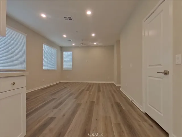 an empty room with wooden floor and windows
