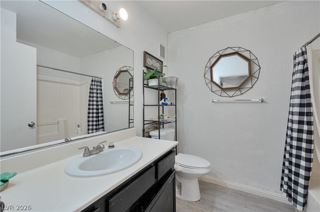 8025 West Russell Road, Unit 1090 Las Vegas, NV 89113 - Photo 16 of 23 Functional bathroom layout features a large vanity mirror and wood-look laminate flooring.