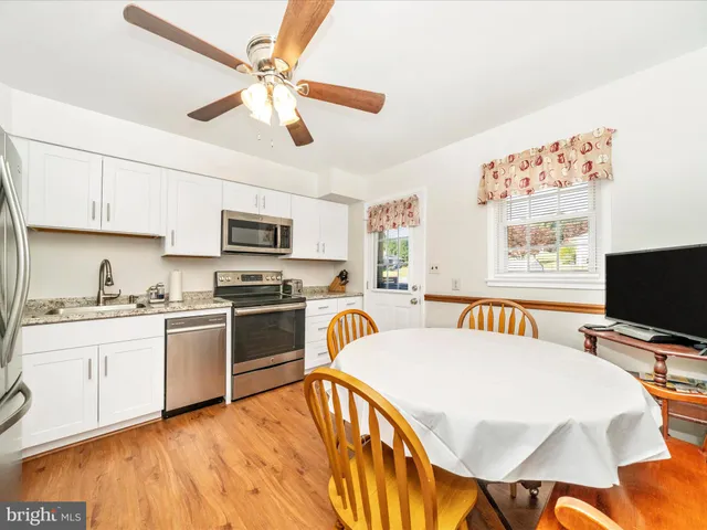 a kitchen with stainless steel appliances a stove a refrigerator a dining table and chairs with wooden floor