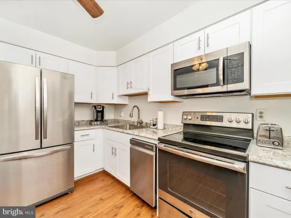 a kitchen with cabinets stainless steel appliances and wooden floor