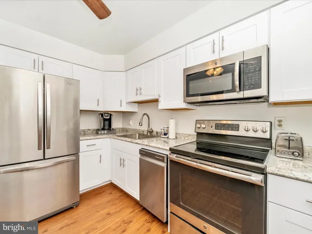 a kitchen with granite countertop white cabinets and stainless steel appliances