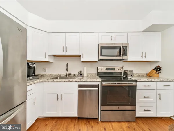 a kitchen with granite countertop white cabinets and stainless steel appliances