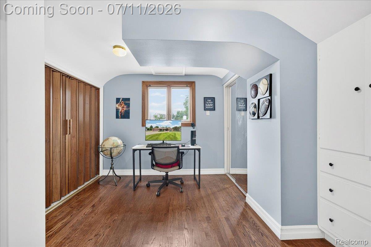 23750 East River Road Grosse Ile, MI 48138 - Photo 19 of 54 Hardwood flooring throughout, featuring a natural wood-trimmed window, built-in white cabinetry, and a full-length mirrored closet door