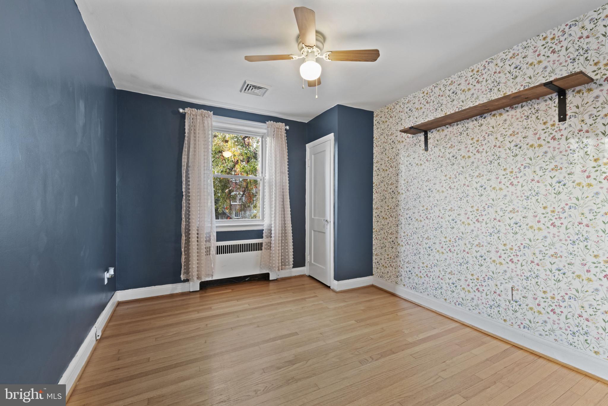 3712 Monterey Road Baltimore, MD 21218 - Photo 23 of 40 an empty room with wooden floor chandelier fan and windows
